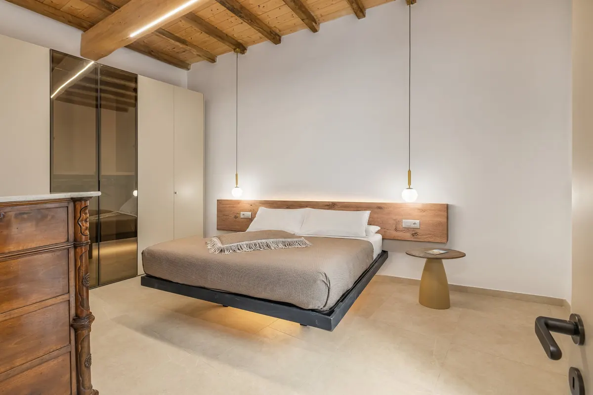 Camera con letto matrimoniale, cassettone antico in noce e armadio a specchio