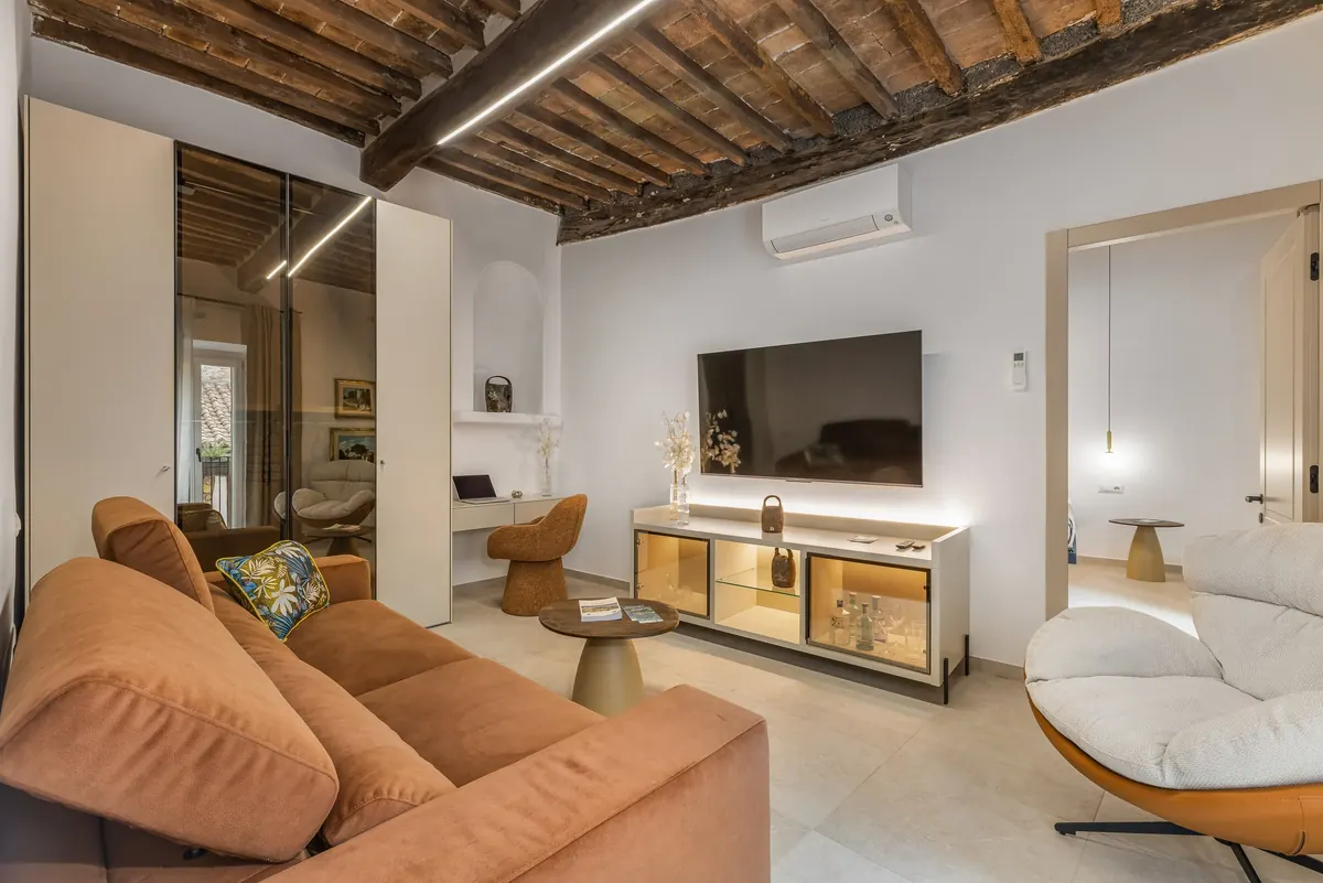 Il living: divano in velluto cognac, poltrona e travi a vista