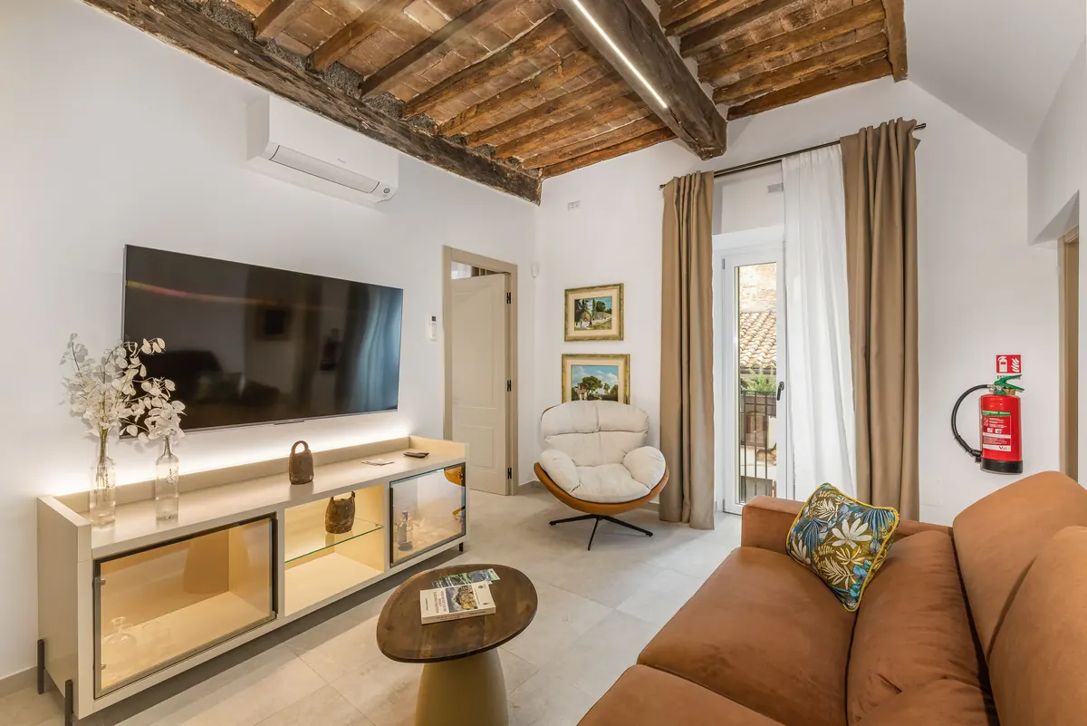 Living con mobile illuminato, poltrona e porta-finestra sul vicolo