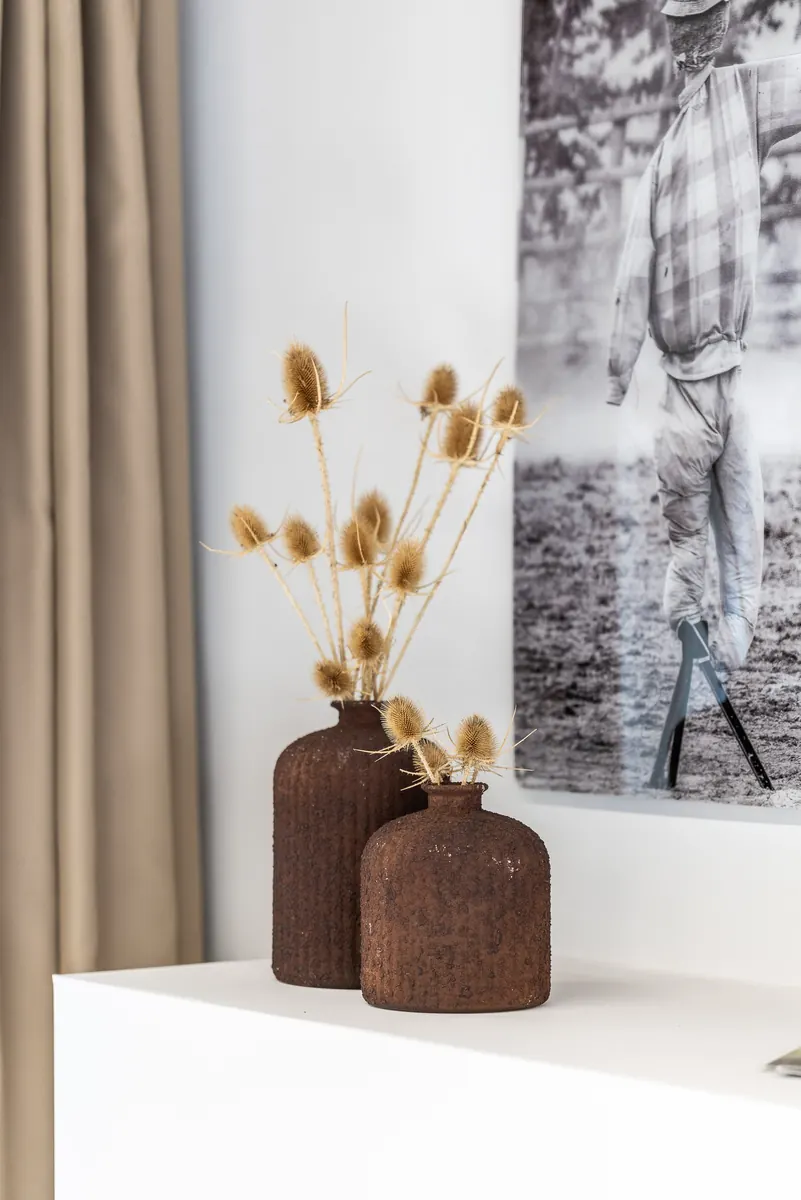 Vasi in terracotta con fiori secchi davanti a una fotografia in bianco e nero