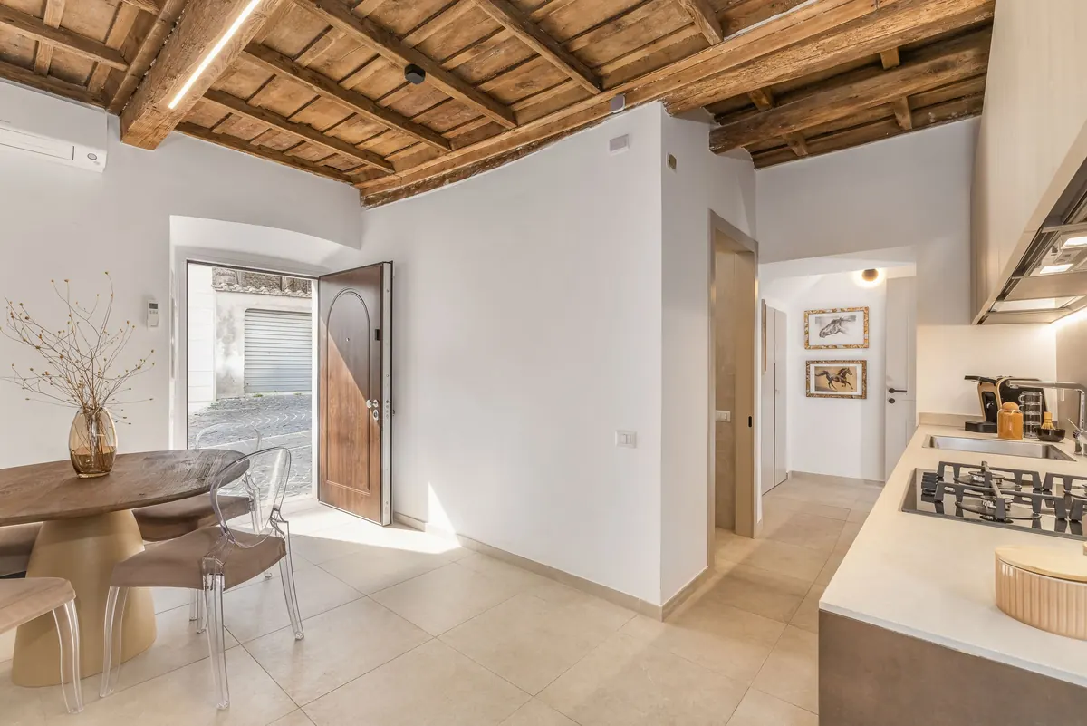 Zona pranzo con la porta d'ingresso in legno aperta sul vicolo